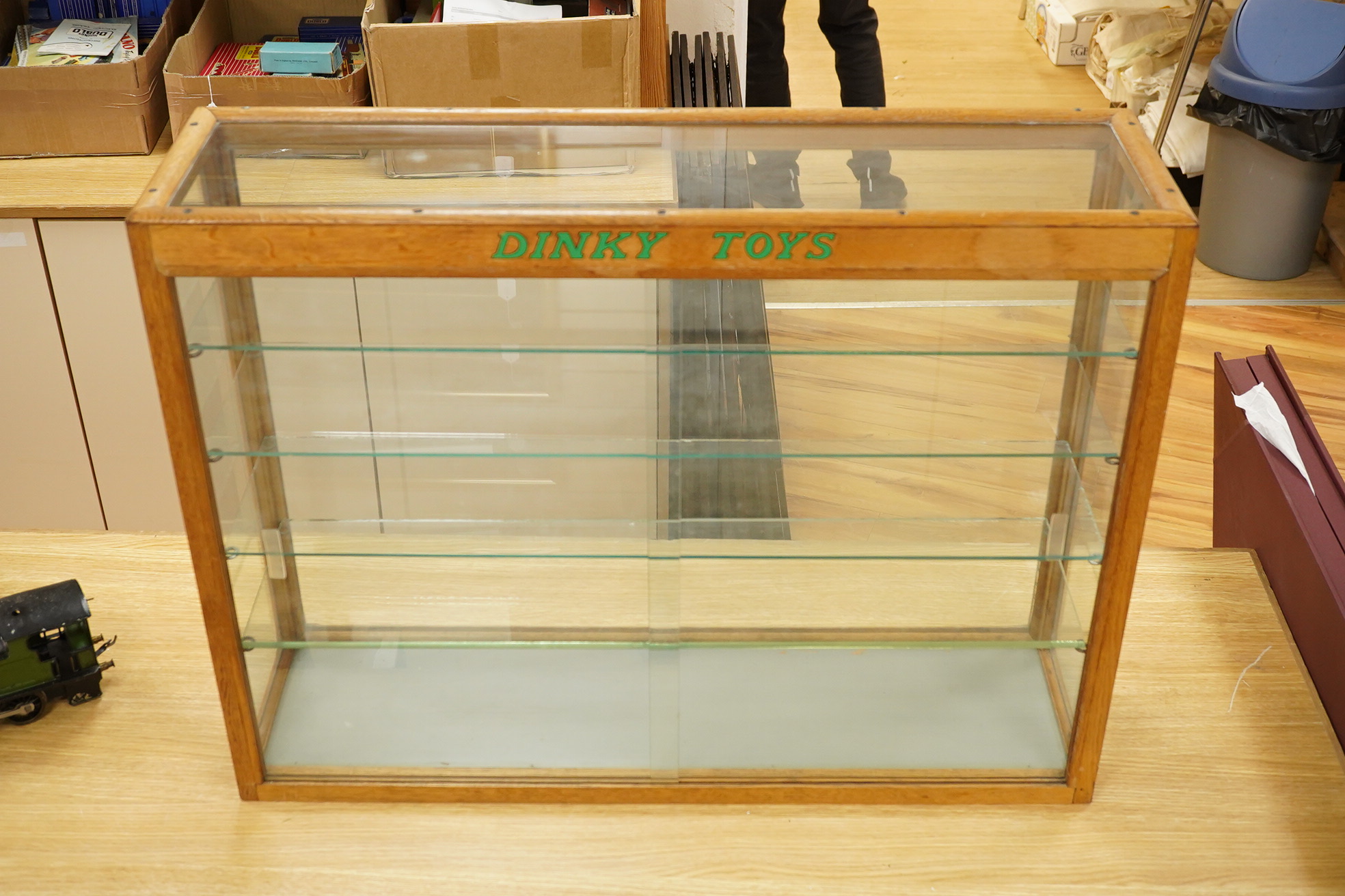 A Dinky Toys glazed oak shop counter retail display cabinet, this is the more scarce ‘front loading’ version of this cabinet, with ‘Dinky Toys’ in green to the top bar, height 61cm, width 81cm, depth 23cm